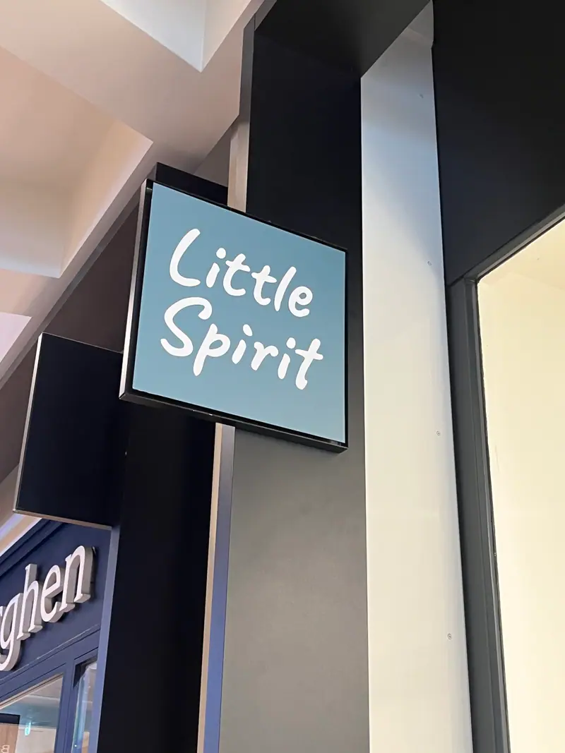 Enseigne drapeau lumineuse Little Spirit sur une façade commerciale