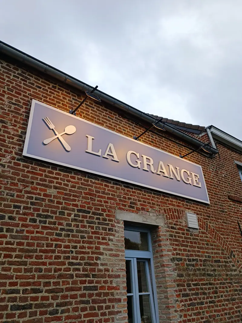 Enseigne La Grange fixée sur la façade en briques du restaurant